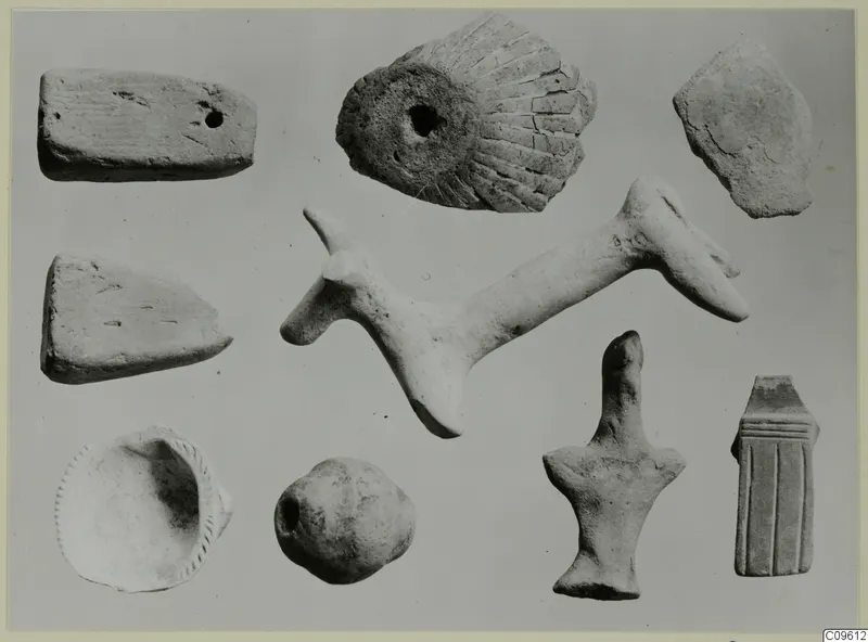 Nine pale objects and fragments on a grey background, including slabs, a shallow dish and a long rod-shaped piece.