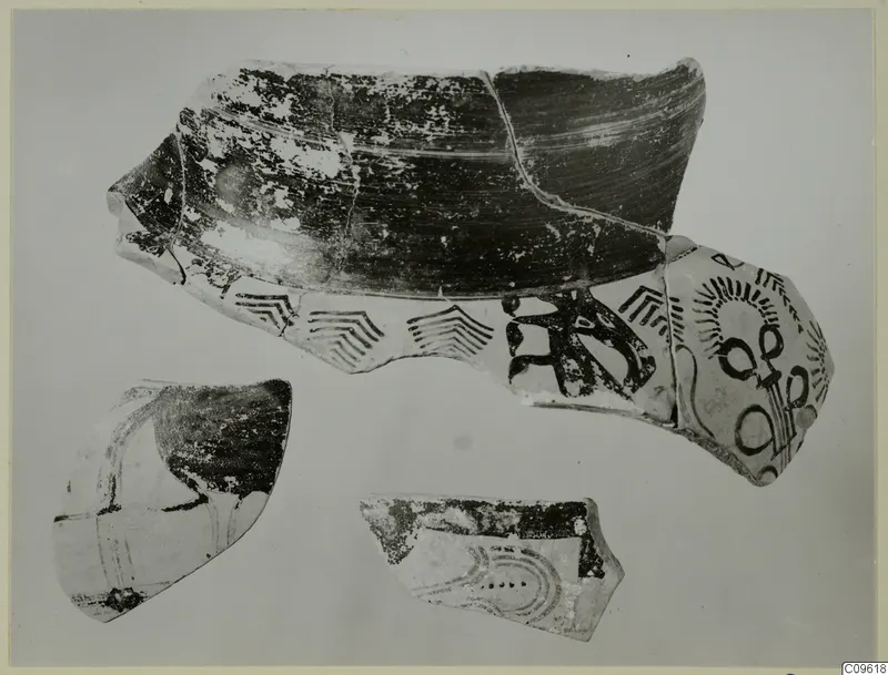 Three Levanto-Helladic pottery sherds with dark painted chevron bands and radiating motifs on a pale surface