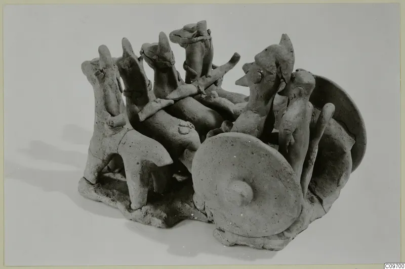 Terracotta group of figures on a rough base, with disc-shaped wheels and a long shaft, from Ayia Irini