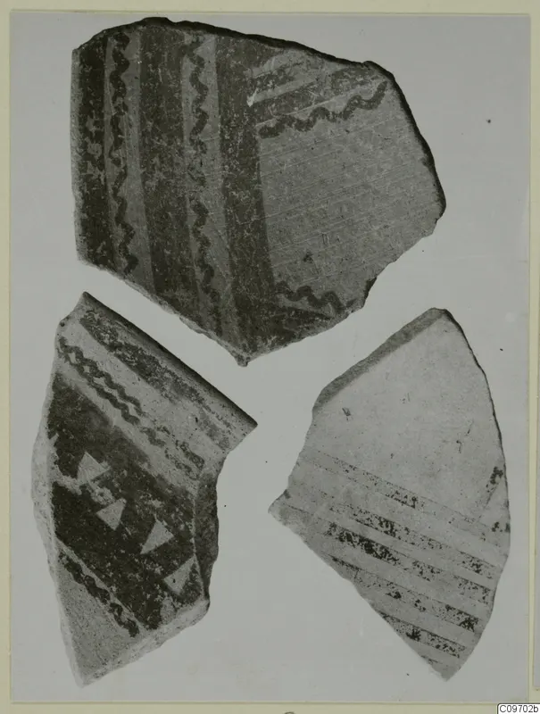 Three pottery sherds with dark painted wavy lines, bands and triangles on a light ground.