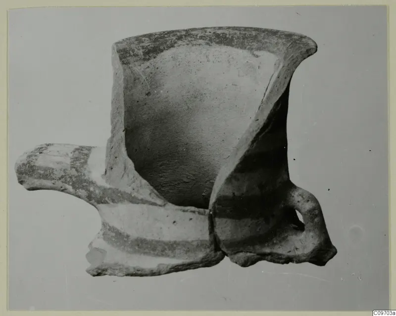 Fragmentary pottery vessel with a flaring rim, a horizontal spout to the left and a loop handle, painted with dark bands