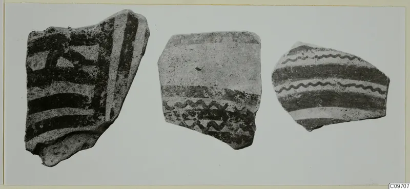 Three painted pottery sherds with dark bands and wavy lines, shown side by side.