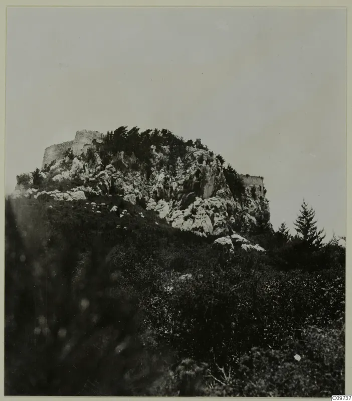 Rocky hill in the Kyrenia Mountains, with ruined stone walls along its summit, trees and shrubs below.
