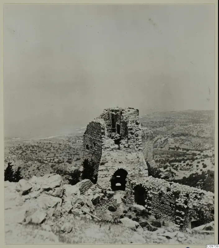 Ruined stone tower on a rocky hilltop with an arched doorway, overlooking scrubby hills and the sea in the Kyrenia Mountains