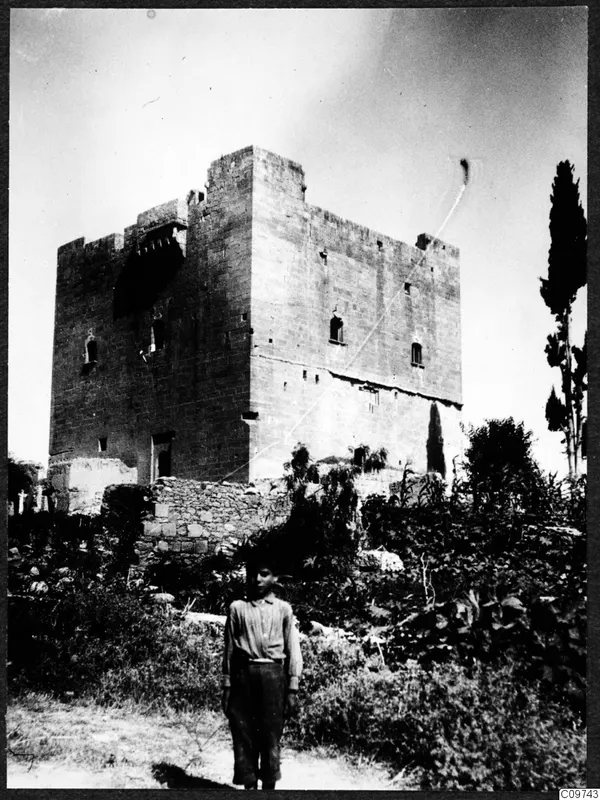 Large square stone tower with battlements, with a boy standing in the foreground, Mesaoria