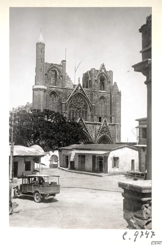 Famagusta: Saint Nicholas cathedral facade with a rose window, with a car and people in the square in front.