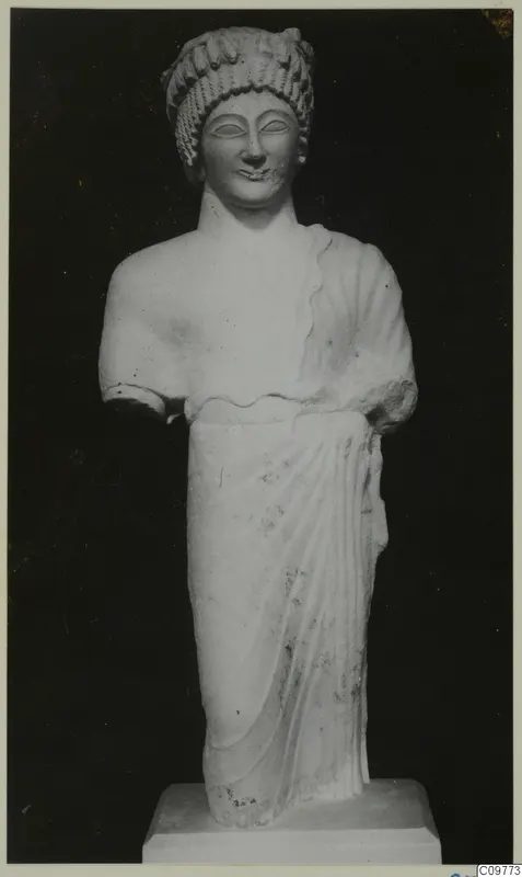 Limestone statue of a standing female figure with both arms broken off, on a square base