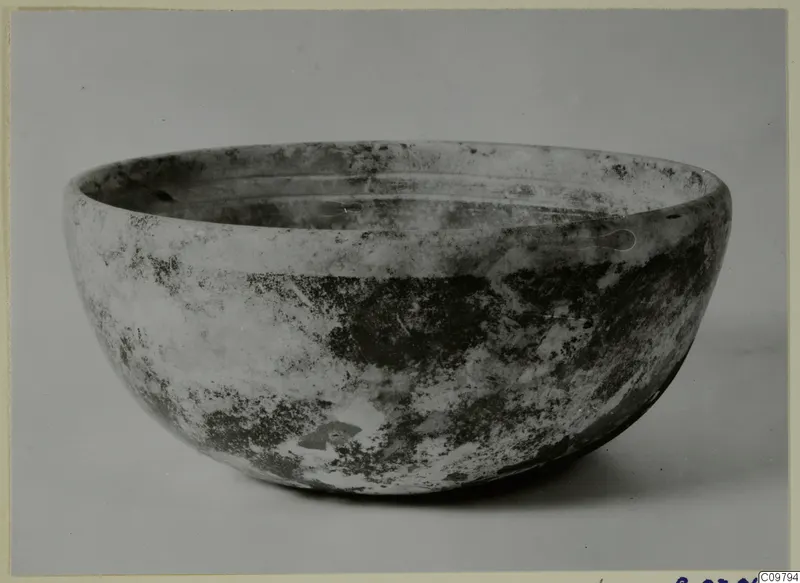 Cast glass bowl with a thick, rounded wall and a weathered, mottled surface