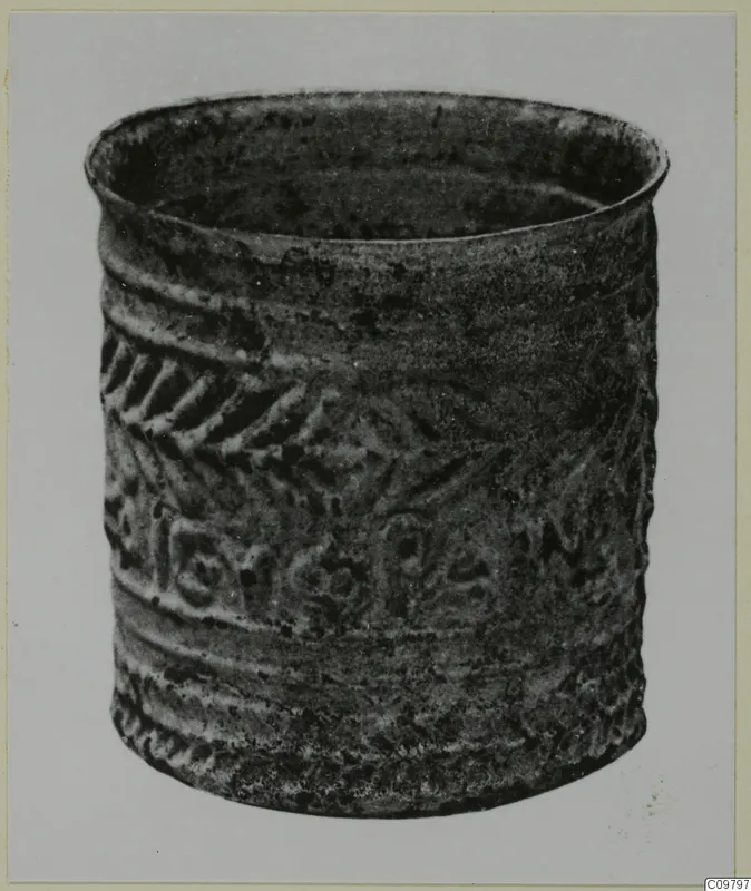 Cylindrical vessel with raised chevron band and rounded motifs, shown against a plain grey backdrop