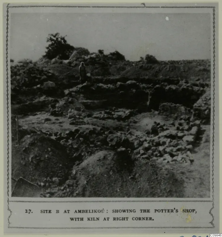 Excavated area of low stone walls and rubble with one standing person on a raised bank