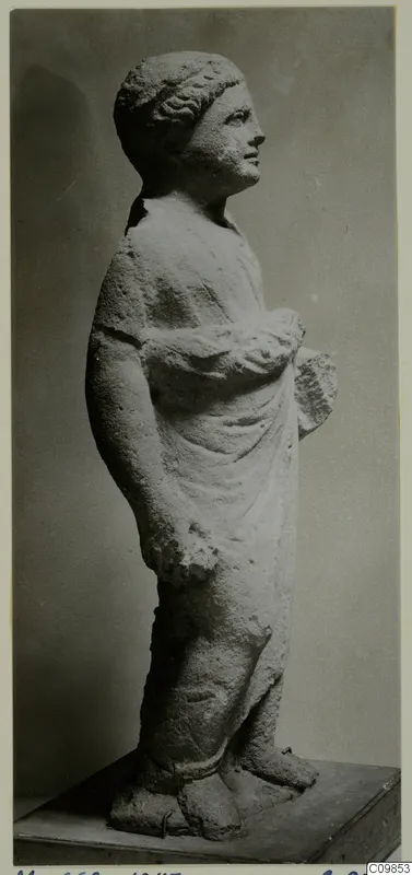 Standing draped statue from Mersinaki, shown in side view on a wooden base