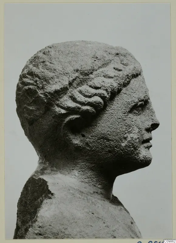 Carved stone head in profile from Mersinaki, facing right, with wavy hair drawn back over the ear.