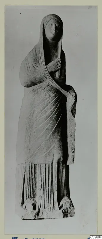 Standing draped female statue in stone, veiled, one hand raised to the chest.