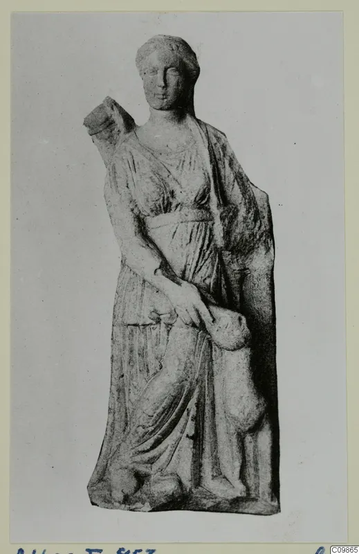 Standing draped female statue with her hair bound up, one arm raised to a block at her shoulder, shown on a grey card mount