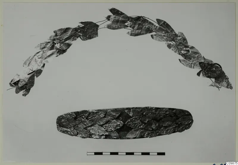 Two pieces of jewellery made of metal leaves: an arched leaf wreath above and an oval band of overlapping leaves below