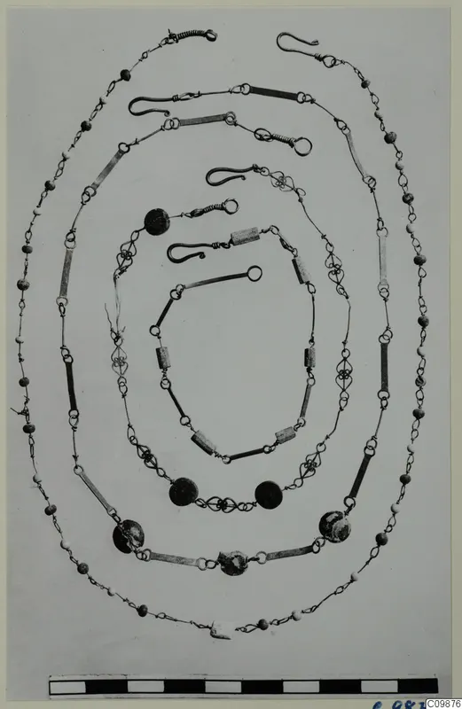 Several nested chains and necklaces of wire links, beads and tubular segments, laid out in oval loops on a plain background.