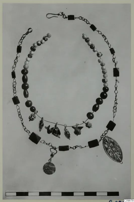 Necklaces and pendants of beads, chain and gold-coloured metal, laid out on a plain background.