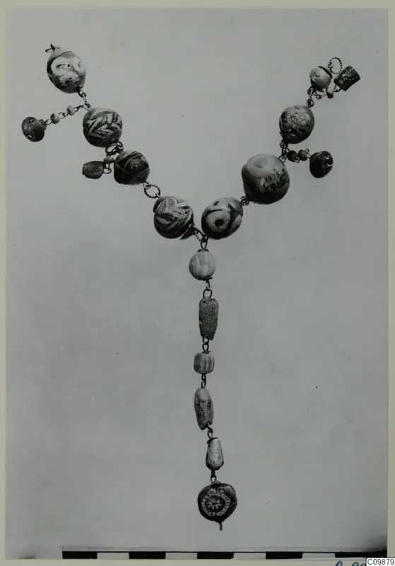 Necklace of glass and stone beads and metal chain, laid out in a V shape.