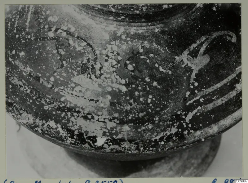 Close view of the rounded lower body and base of a dark-surfaced painted vessel, with worn decoration