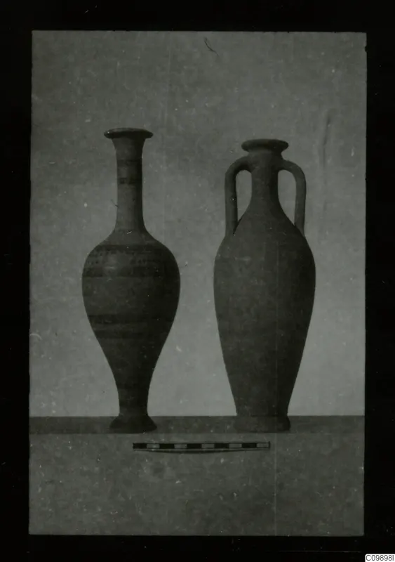 Two pottery vessels side by side, a tall one with painted bands and a two-handled jar, with a scale bar in front