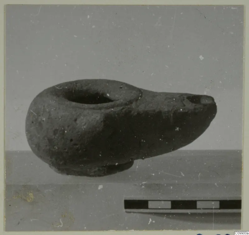 Clay lamp with a round filling hole and pinched spout, shown in side view beside a scale bar.