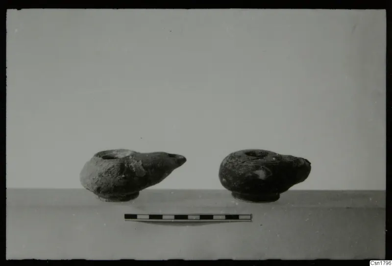Two pottery oil lamps with spouts, with a scale bar in front of them