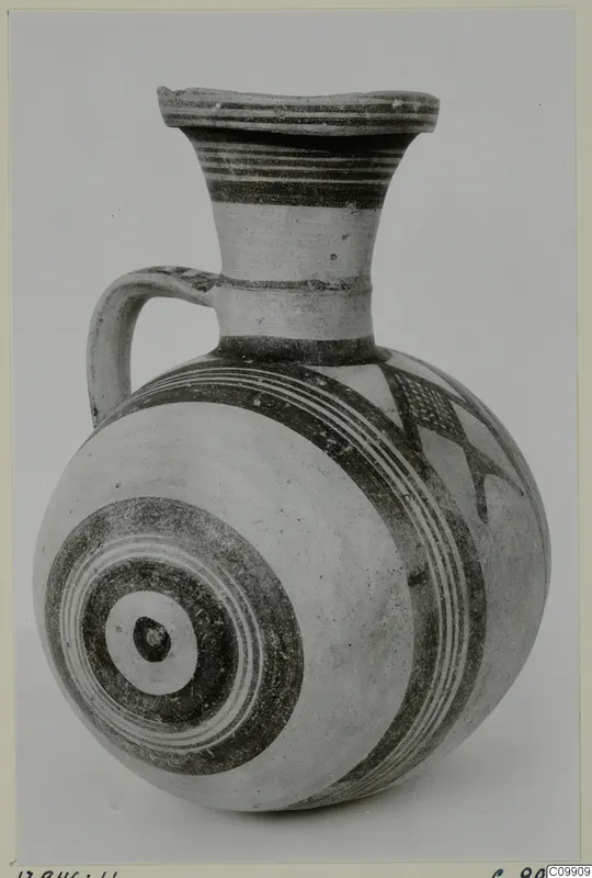 White Painted II jug with a flared rim, a strap handle and dark bands and concentric circles on a pale body
