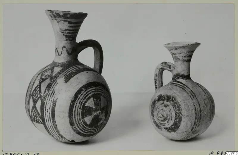 Jug and juglet side by side, decorated with dark painted bands, concentric circles and triangles.