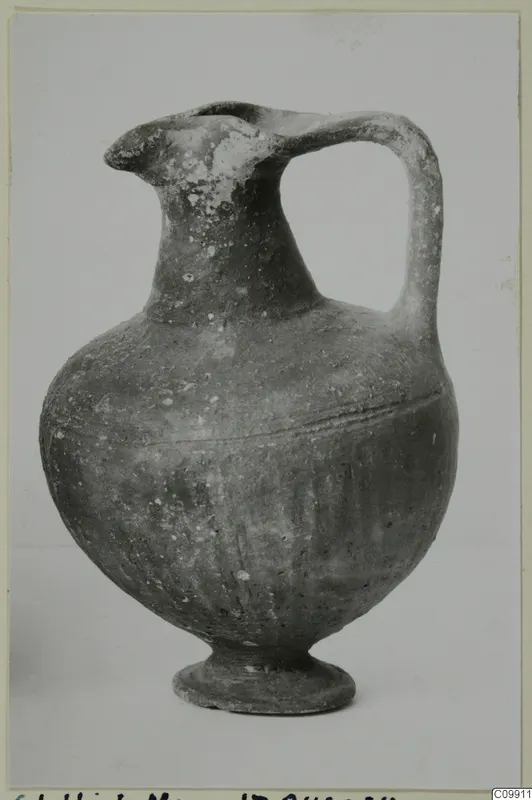 Black Slip I-VI pottery jug with a single handle, pinched spout and low ring base