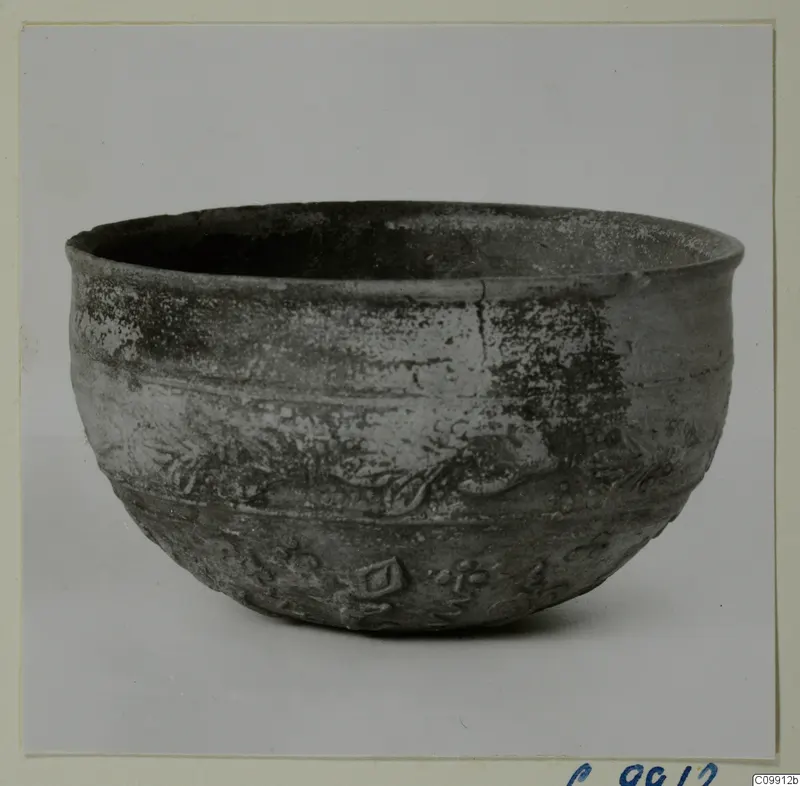 Grey-black pottery bowl with a wide mouth and relief decoration of bands and motifs on its body