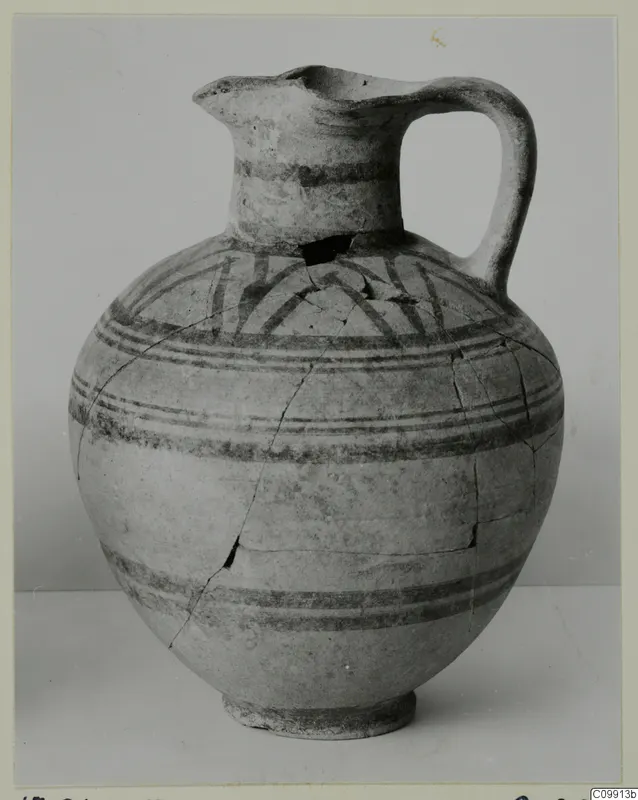 Pottery Bichrome II jug with dark painted bands and arcs on the shoulder, shown against a grey backdrop