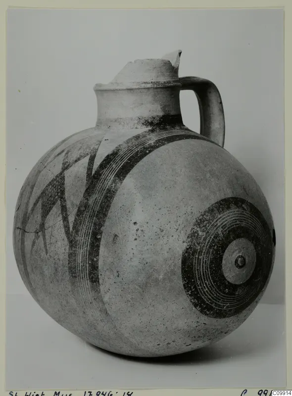 Round-bodied jug with a tall neck, one handle and dark painted bands and concentric circles on a pale surface.