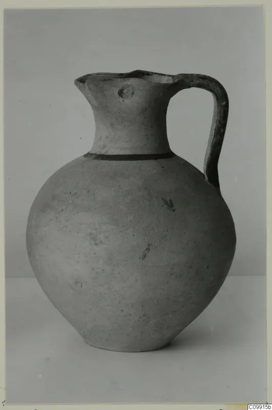 Pottery White Painted III-1 jug with a round body, a dark band at the neck and a strap handle