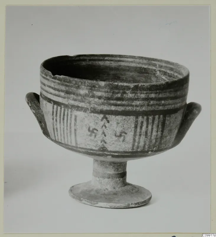 Pottery Bichrome III footed bowl with two small handles, painted bands and hooked cross and chevron motifs.