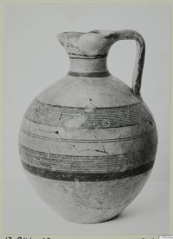 Jug with a trefoil mouth, a strap handle and horizontal bands of painted lines on a round body.