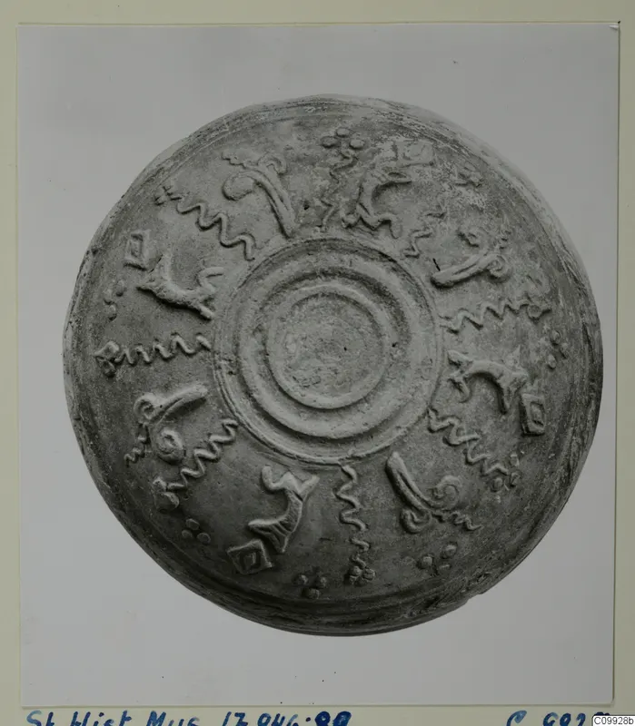 Shallow bowl seen from above, with raised concentric rings at the centre and relief motifs around the body
