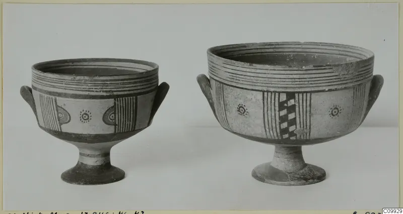 Two painted pottery footed bowls with side handles, shown side by side against a plain background.