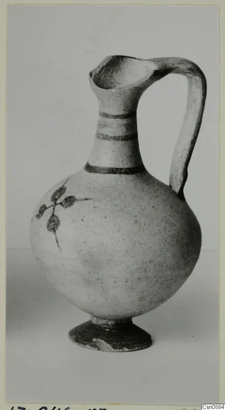 Pottery Bichrome IV jug with dark painted bands on the neck and a painted leaf sprig on the body