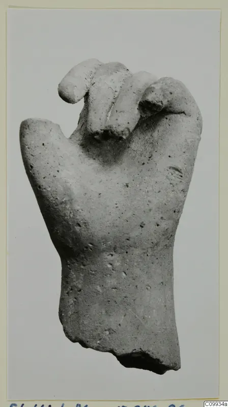 Fragment of a hand, fingers curled, broken off at the wrist, photographed on a card mount.
