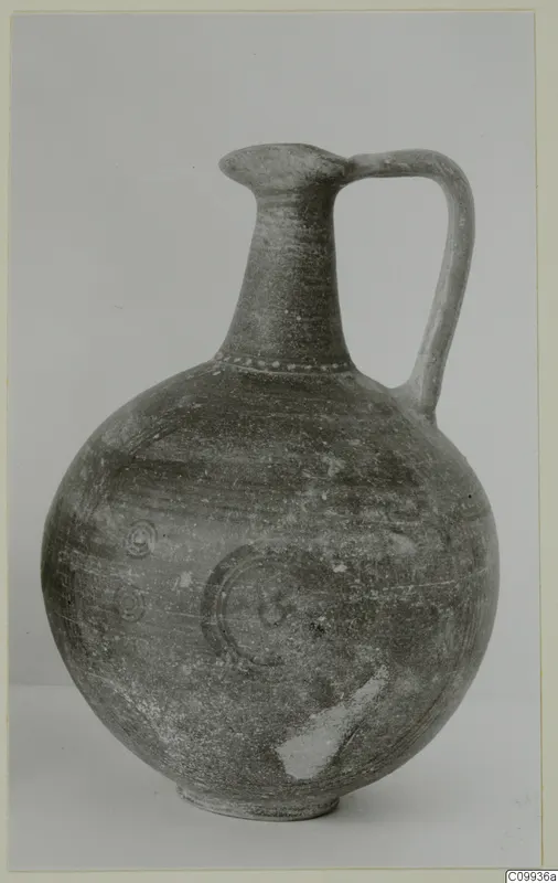 Globular jug with a tall neck and strap handle, decorated with concentric circles and a band of dots at the neck