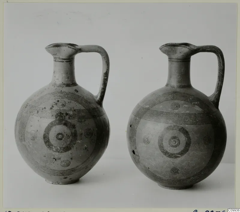 Two painted pottery jugs with single loop handles, standing side by side