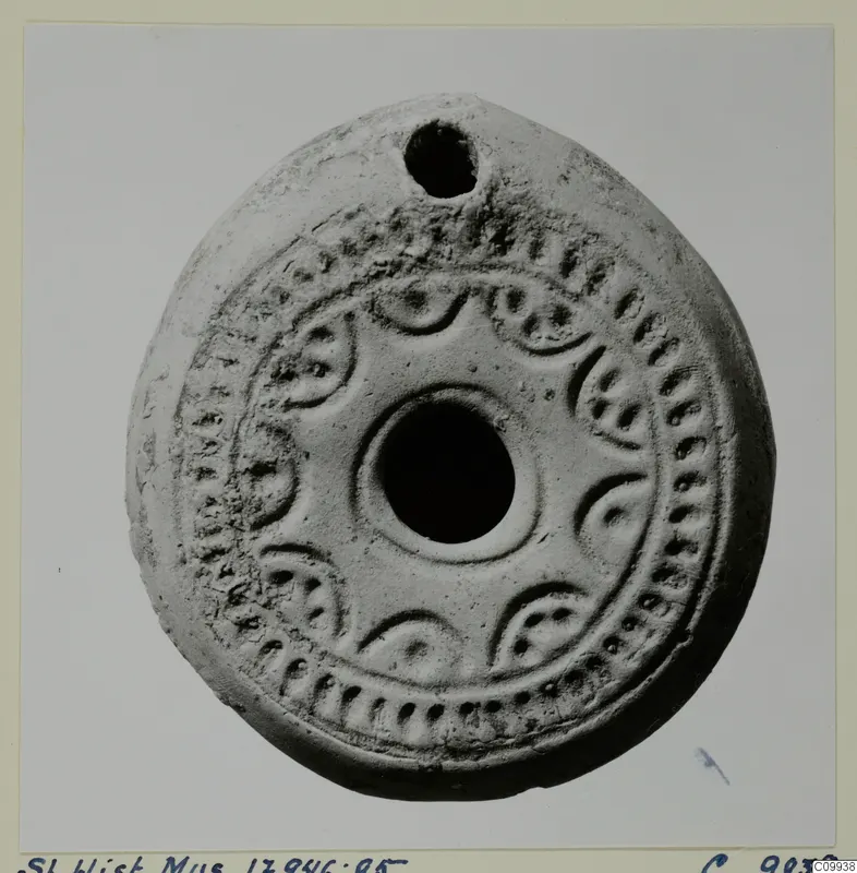 Terracotta lamp with a filling hole at the top and a ring of raised decoration around the central nozzle.
