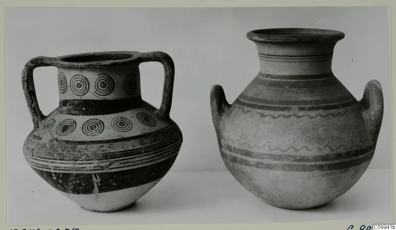 Two two-handled clay vessels side by side, the left one decorated with rows of concentric circles and dark bands.