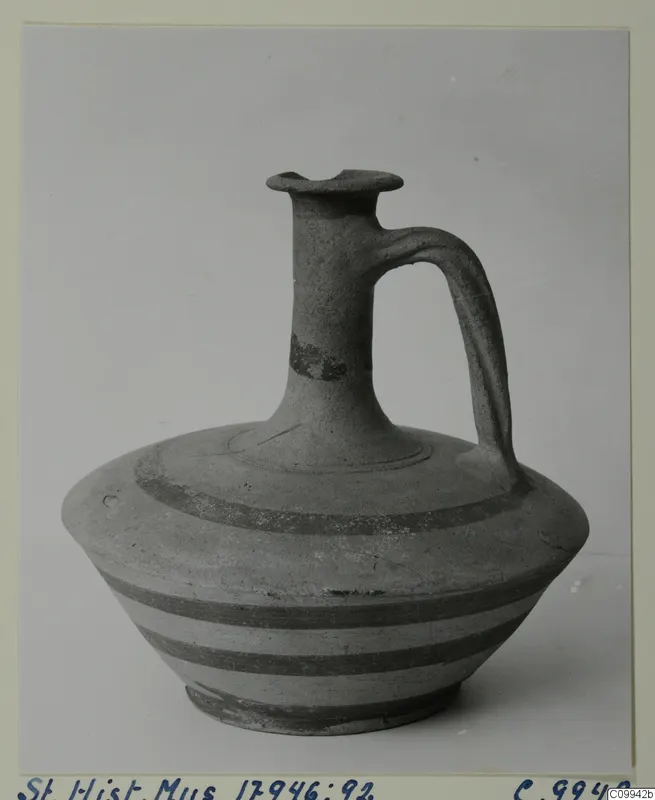 Jug with a flared mouth, one loop handle and dark horizontal bands, photographed against a plain background