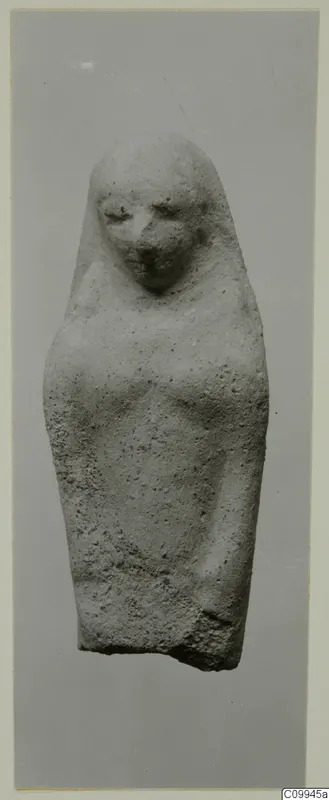 Stone statue of a standing figure with a veil or hood over the head, photographed against a grey background