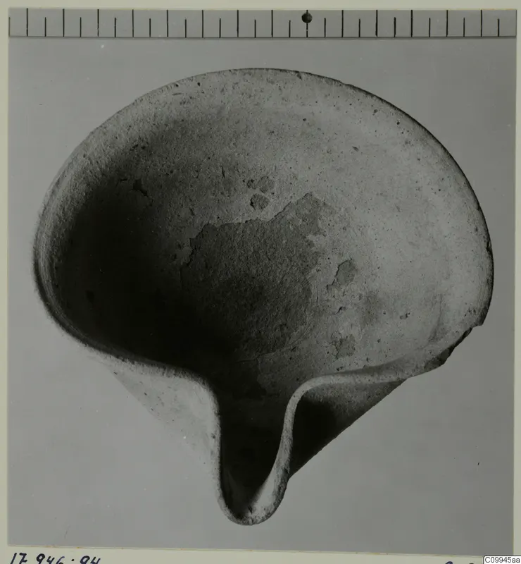 Stone bowl with a pinched lip projecting at one side, photographed from above with a scale bar along the top edge.