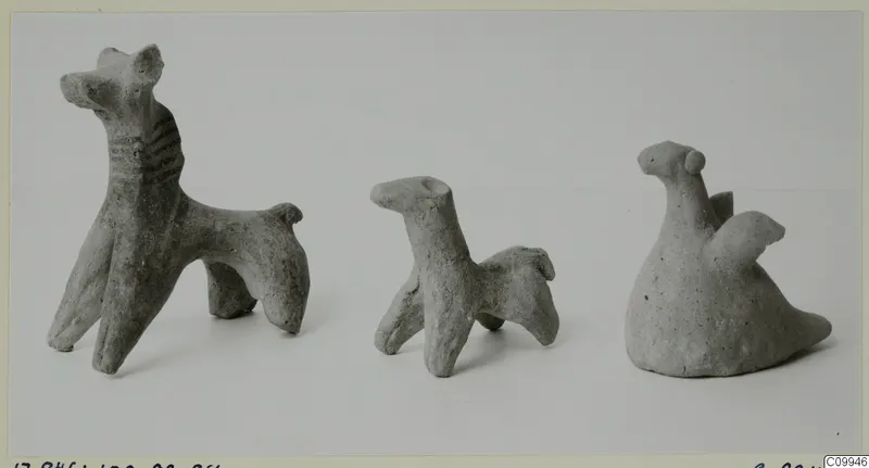 Three small terracotta animal figurines standing in a row against a plain background