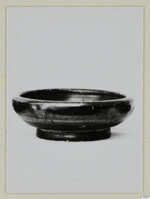 Black-glazed bowl with a low ring foot, photographed in side view against a plain background