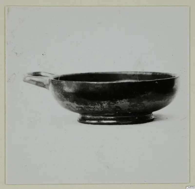 Black-glazed bowl with a single horizontal handle and a low ring foot.