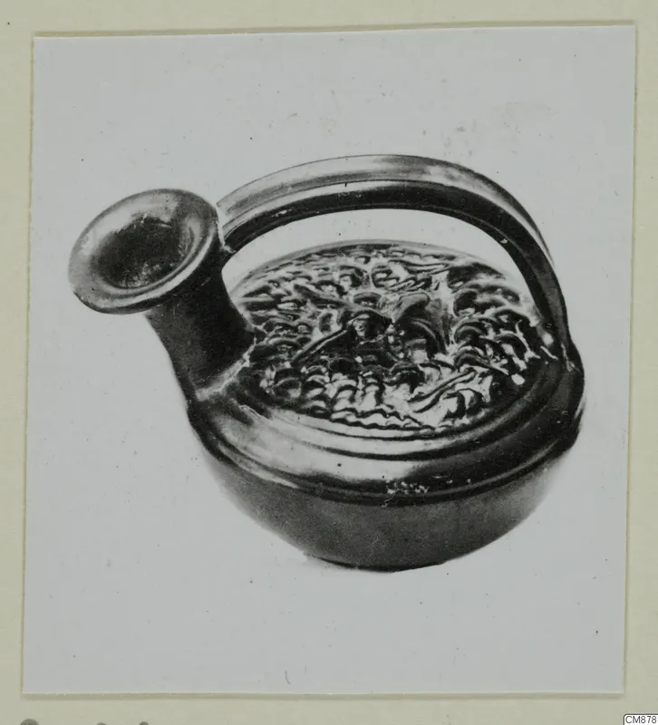 Black-glazed pottery vessel with a flaring spout, loop handle and relief decoration on the shoulder